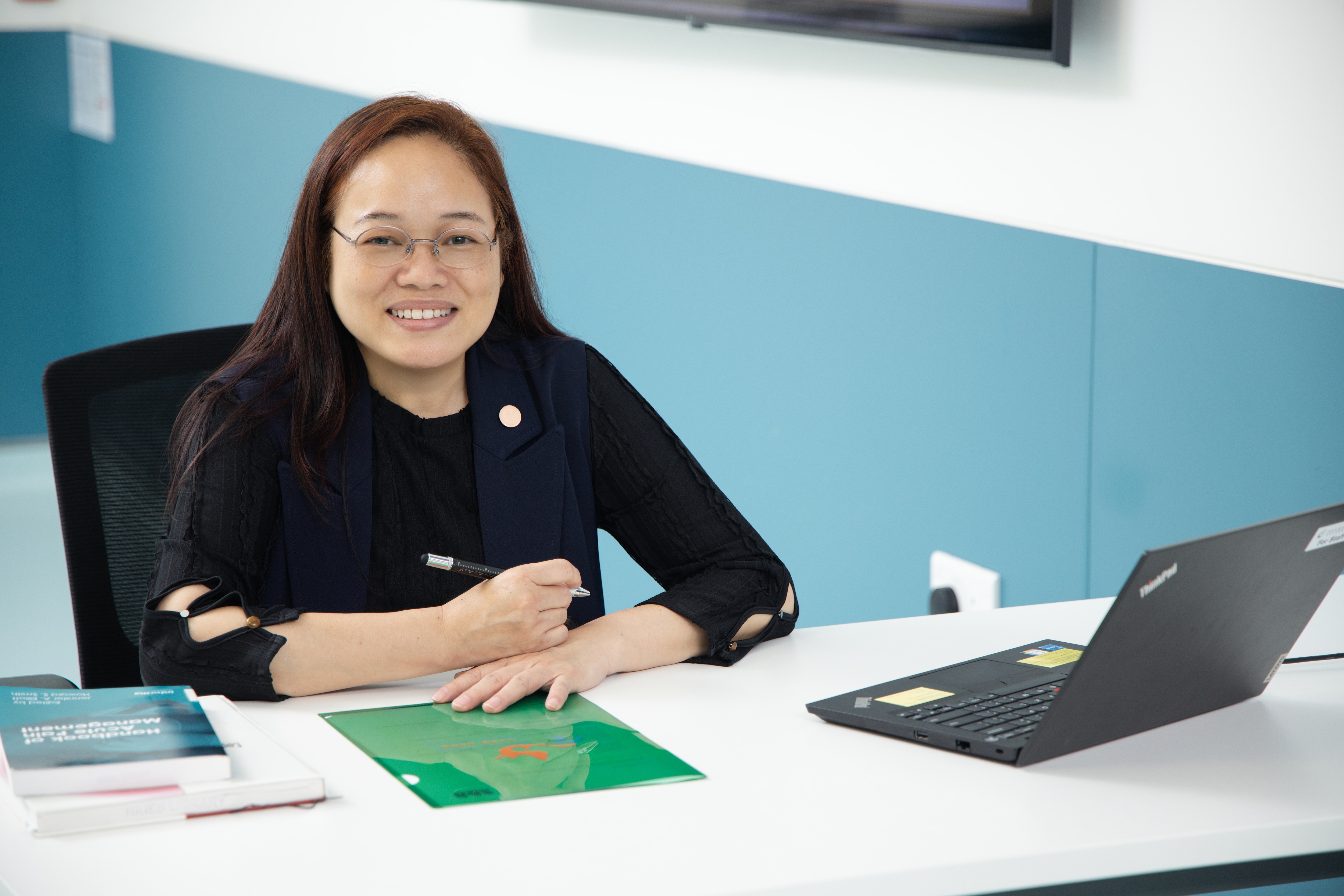 Woman (Sanne Fong) on desk with pen and laptop